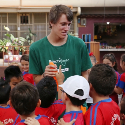 A volunteer and the kids around him during sport practice in Costa Rica Children in Costa Rica around a Projects Abroad volunteer during a sport practice